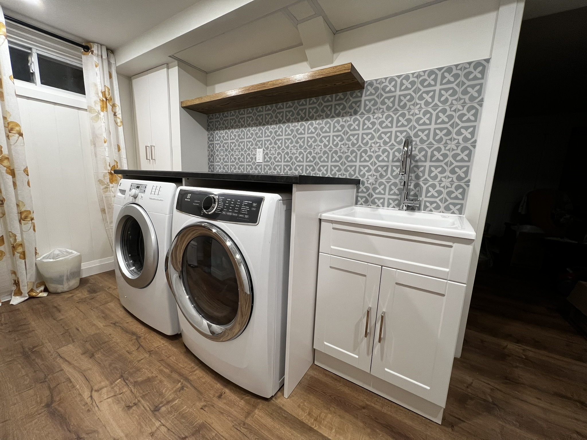 Completed laundry area with patterned tile and custom shelving