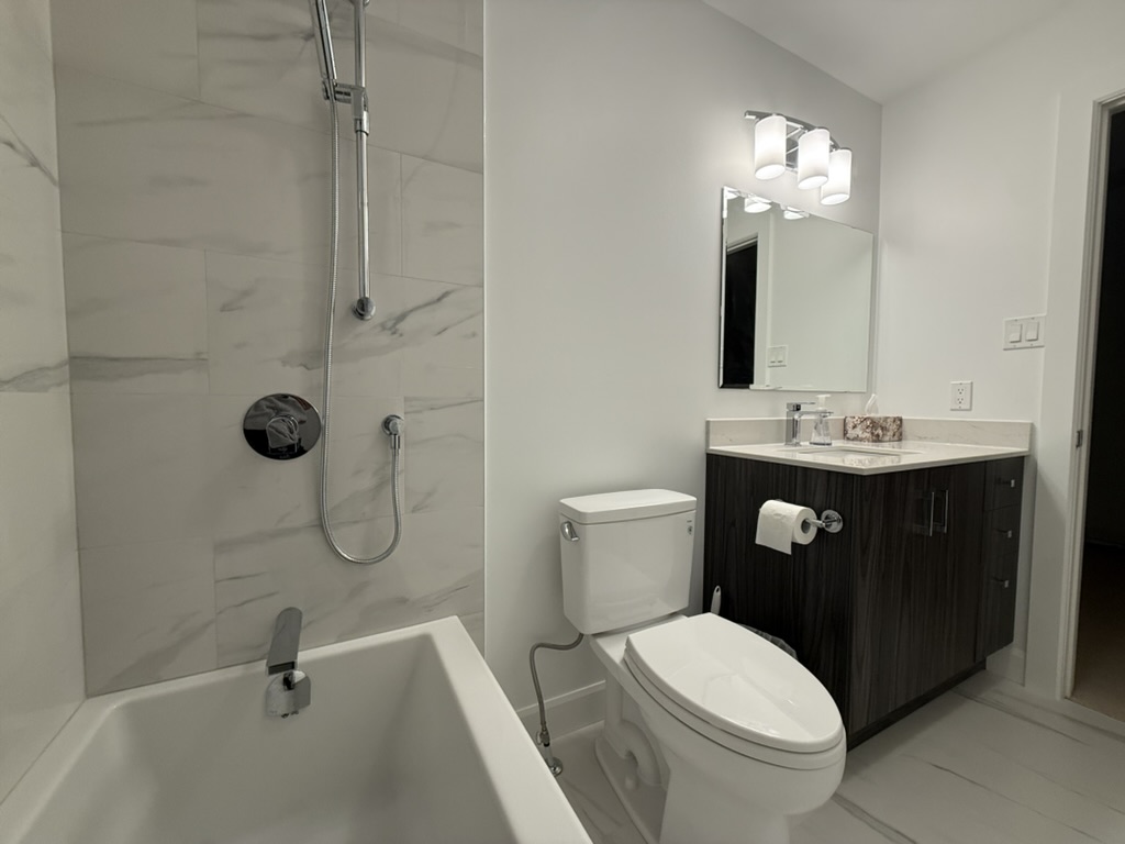 Completed bathroom with tiled tub surround and new vanity